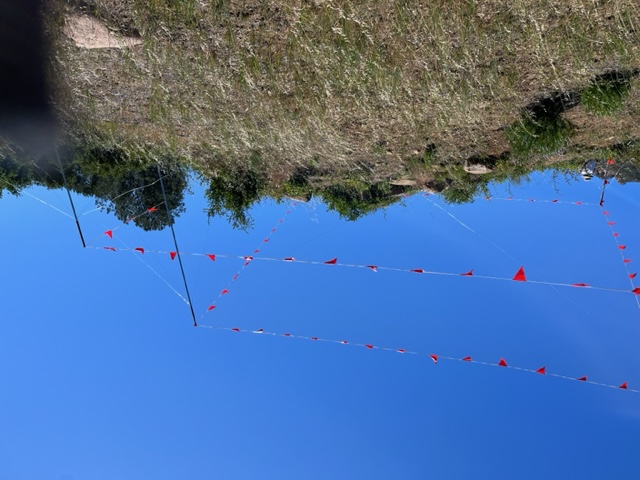 Story pole frame with red flagging on hillside